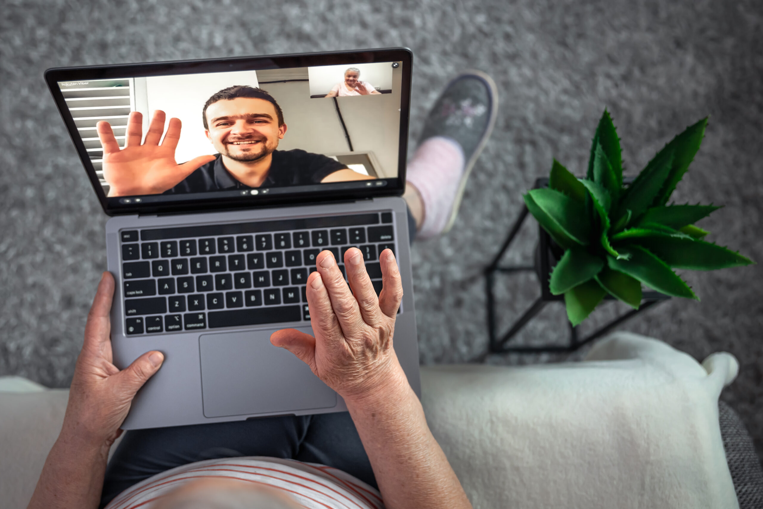 An old woman communicates with her son via video link through a laptop.